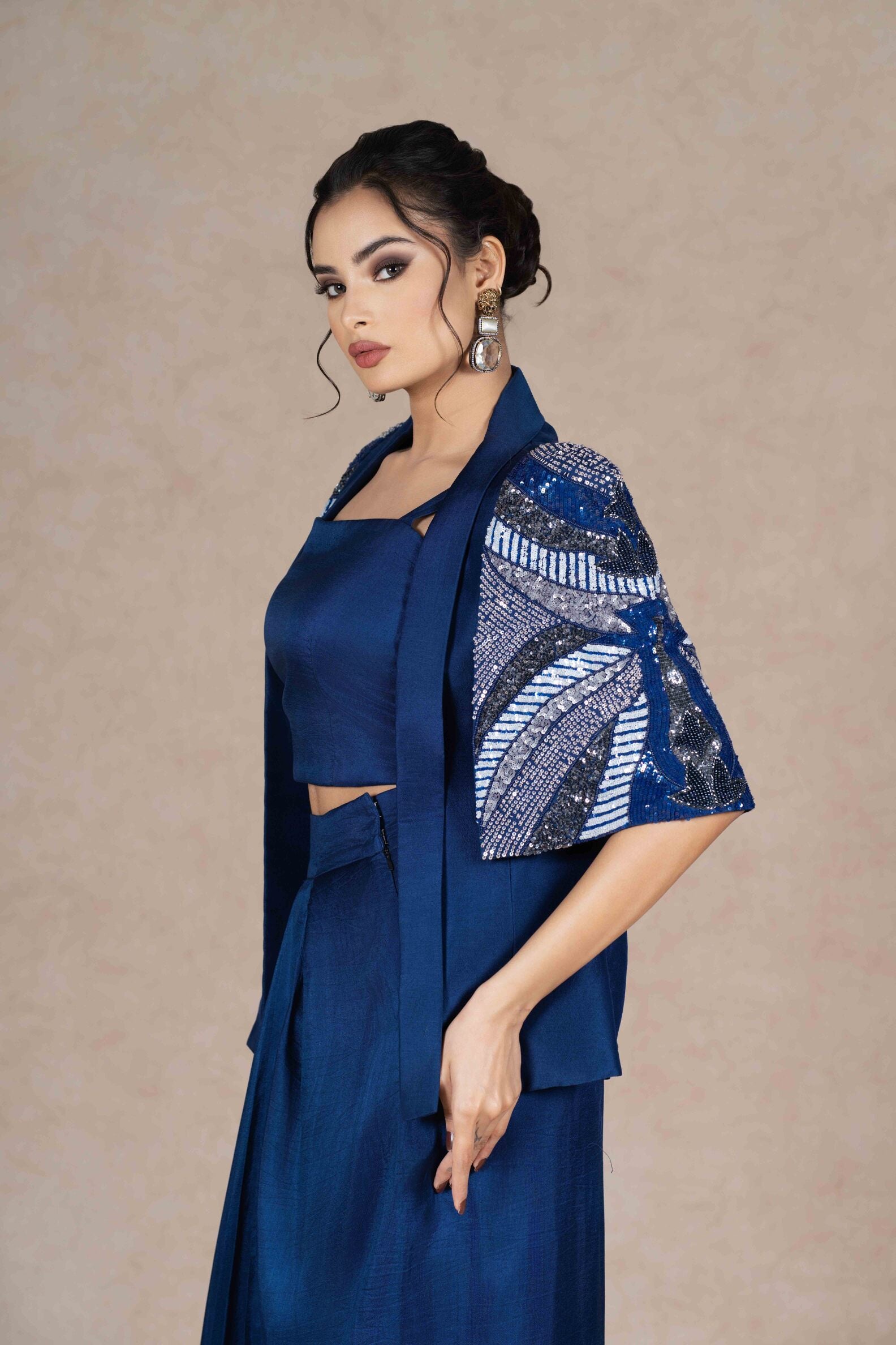 Royal blue embroidered jacket with cape sleeves, sweetheart neckline bustier, and pleated floor-length skirt. Elegant festive or formal ensemble.