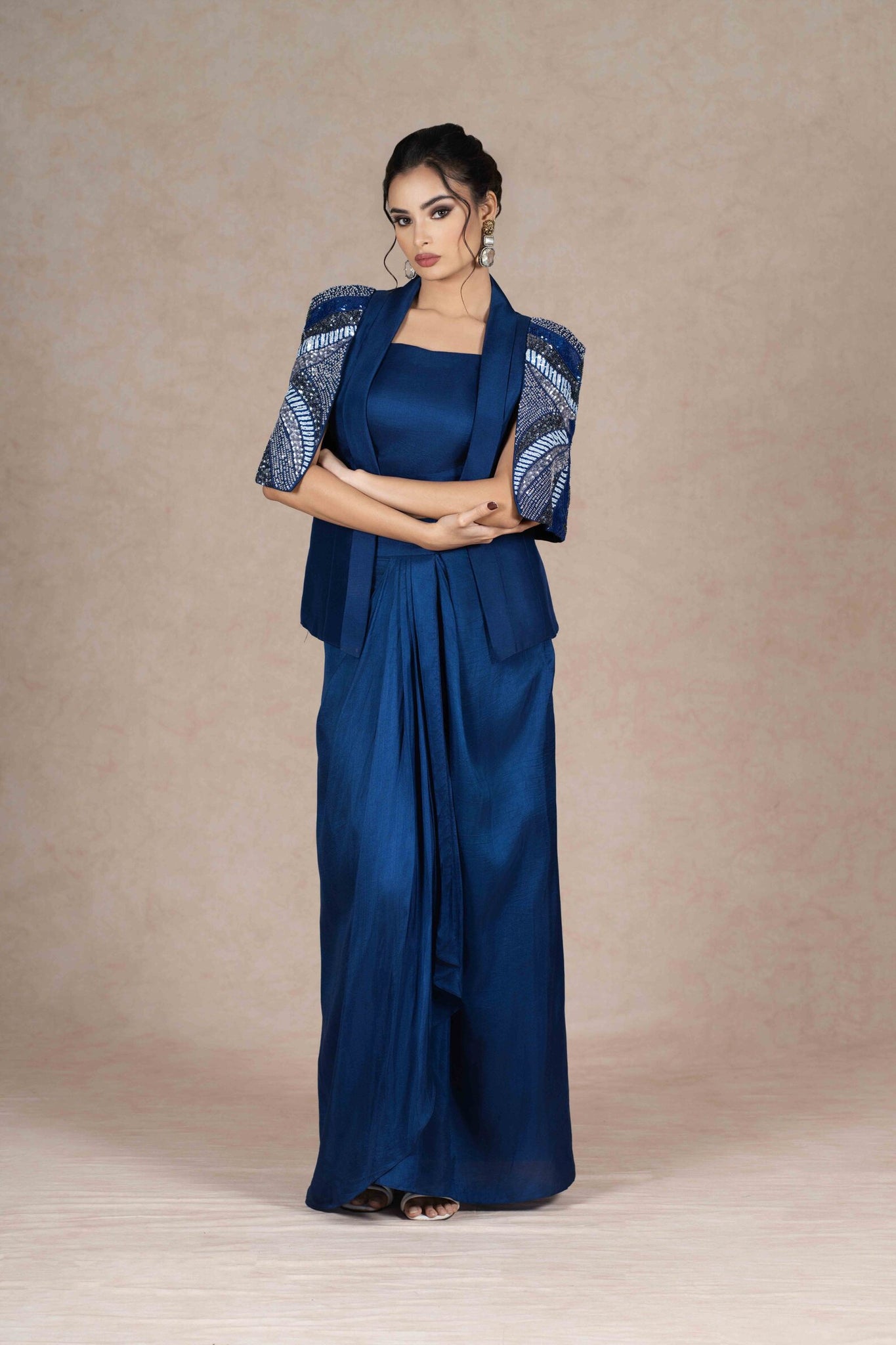 Royal blue embroidered jacket with cape sleeves, sweetheart neckline bustier, and pleated floor-length skirt. Elegant festive or formal ensemble.