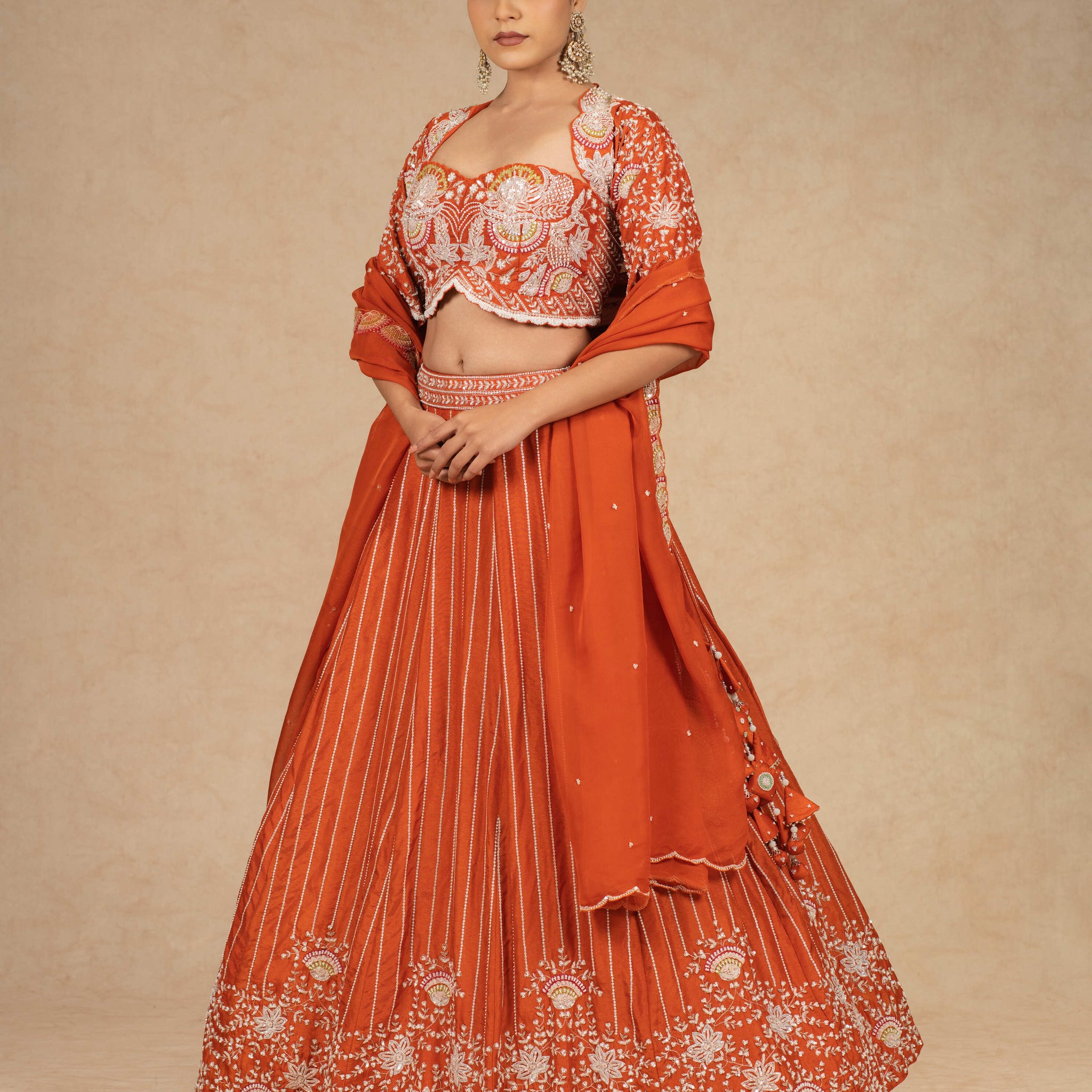 Designer rust lehenga choli with intricate embroidery, paired with a matching organza dupatta.