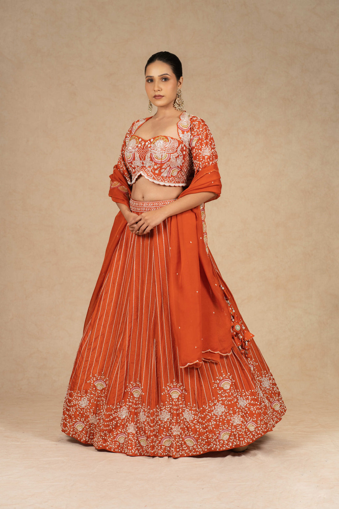 Designer rust lehenga choli with intricate embroidery, paired with a matching organza dupatta.