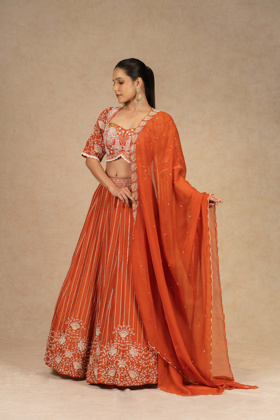 Designer rust lehenga choli with intricate embroidery, paired with a matching organza dupatta.