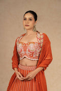 Close-up of the rust lehenga choli, highlighting the intricate embroidery on the choli and the delicate organza dupatta.