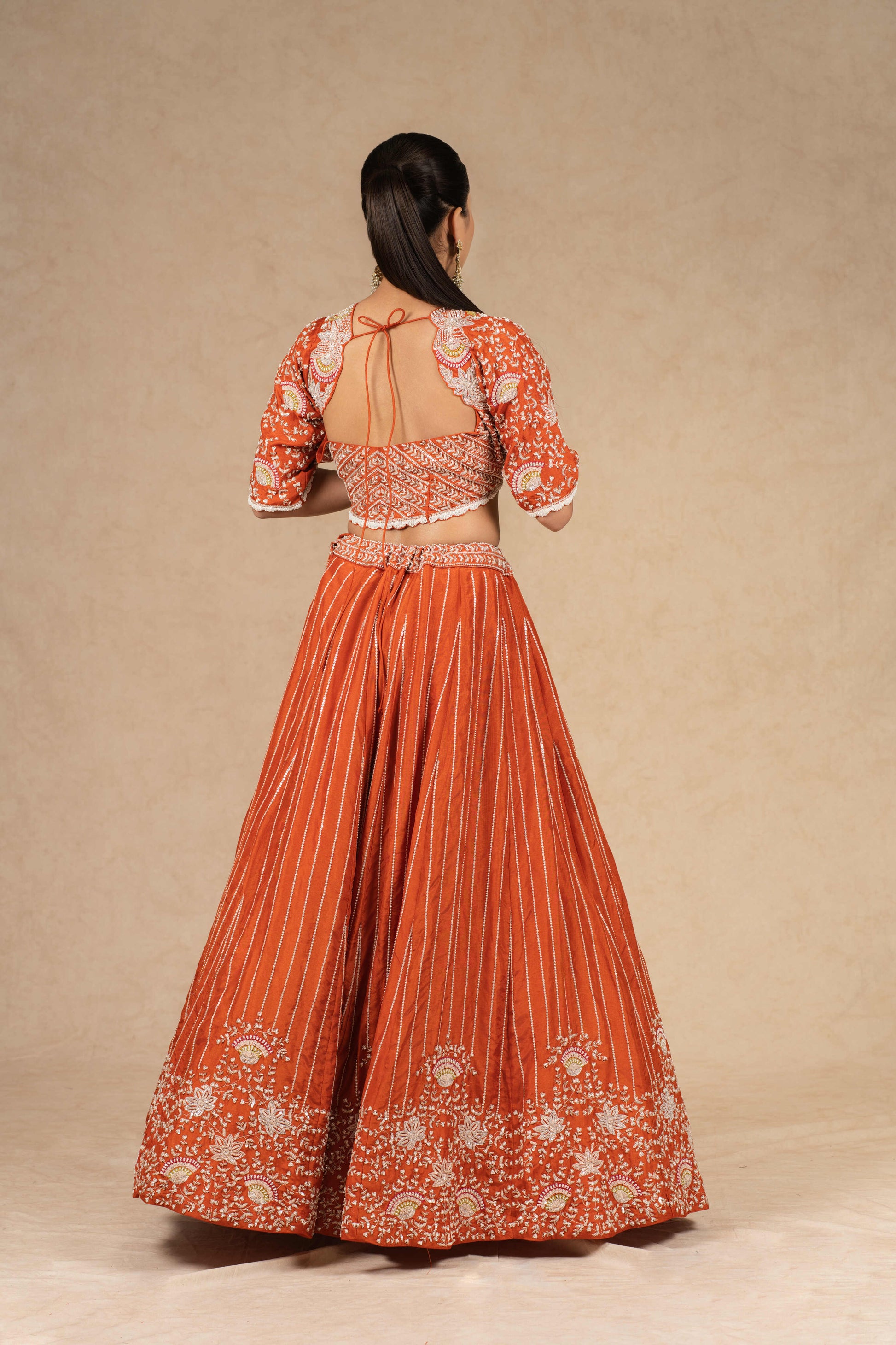 Back view of the rust lehenga choli, featuring an embroidered blouse with a stylish cutout design.