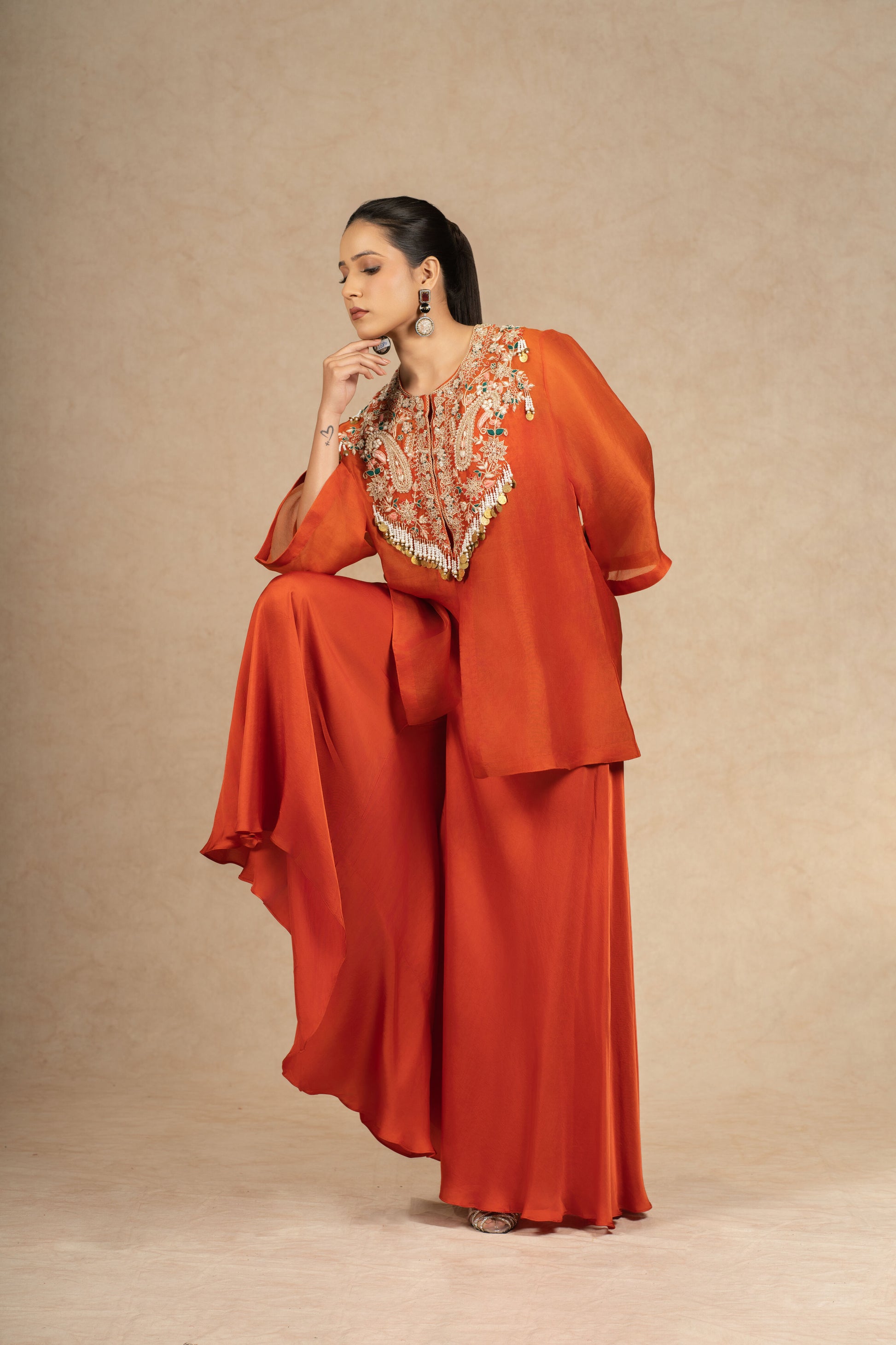 Model striking a dramatic pose in a Rust Organza Indo-Western outfit, accentuating the fluid movement of the fabric.