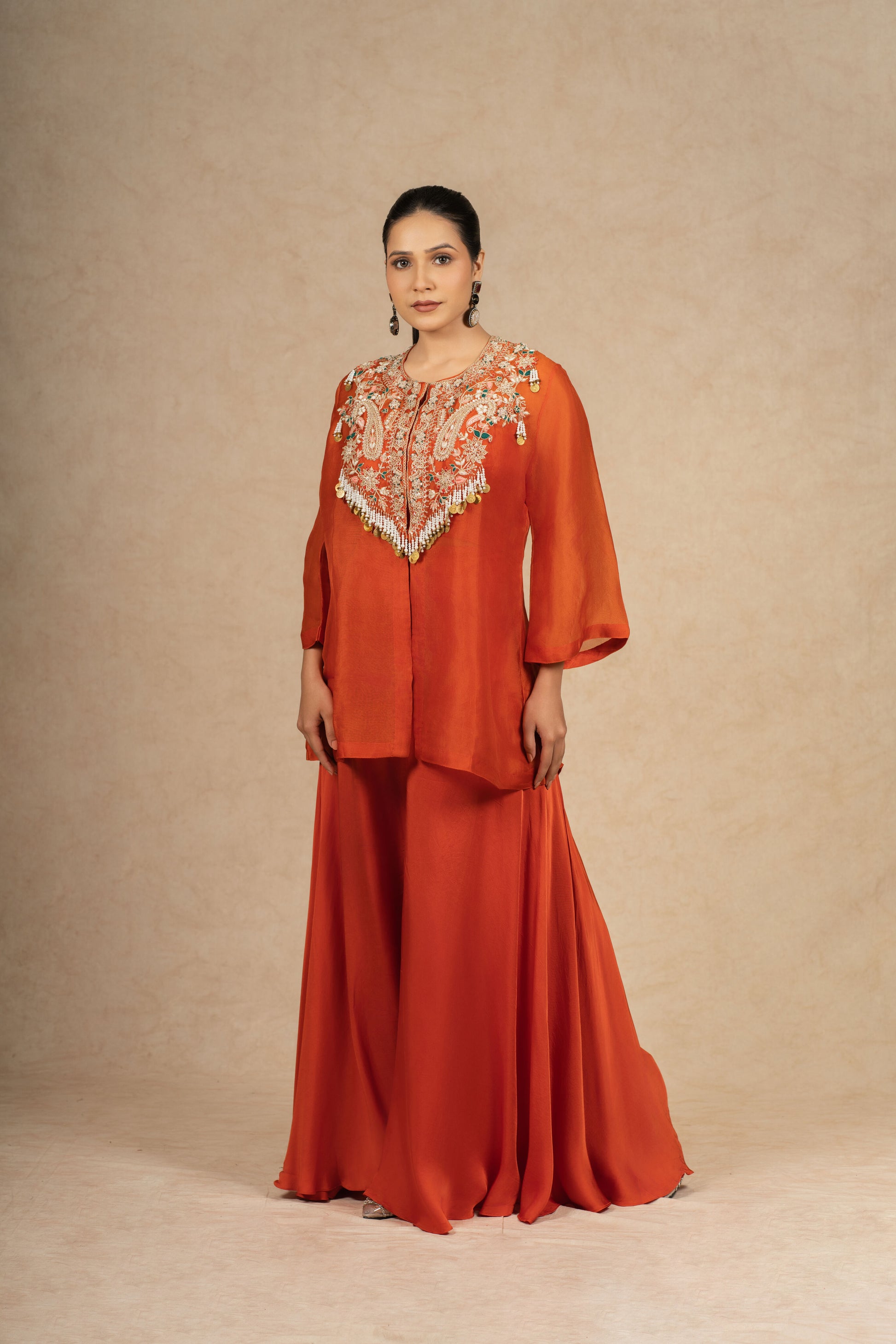 Model showcasing a Rust Organza Indo-Western outfit with intricate embroidery on the bodice and flared pants