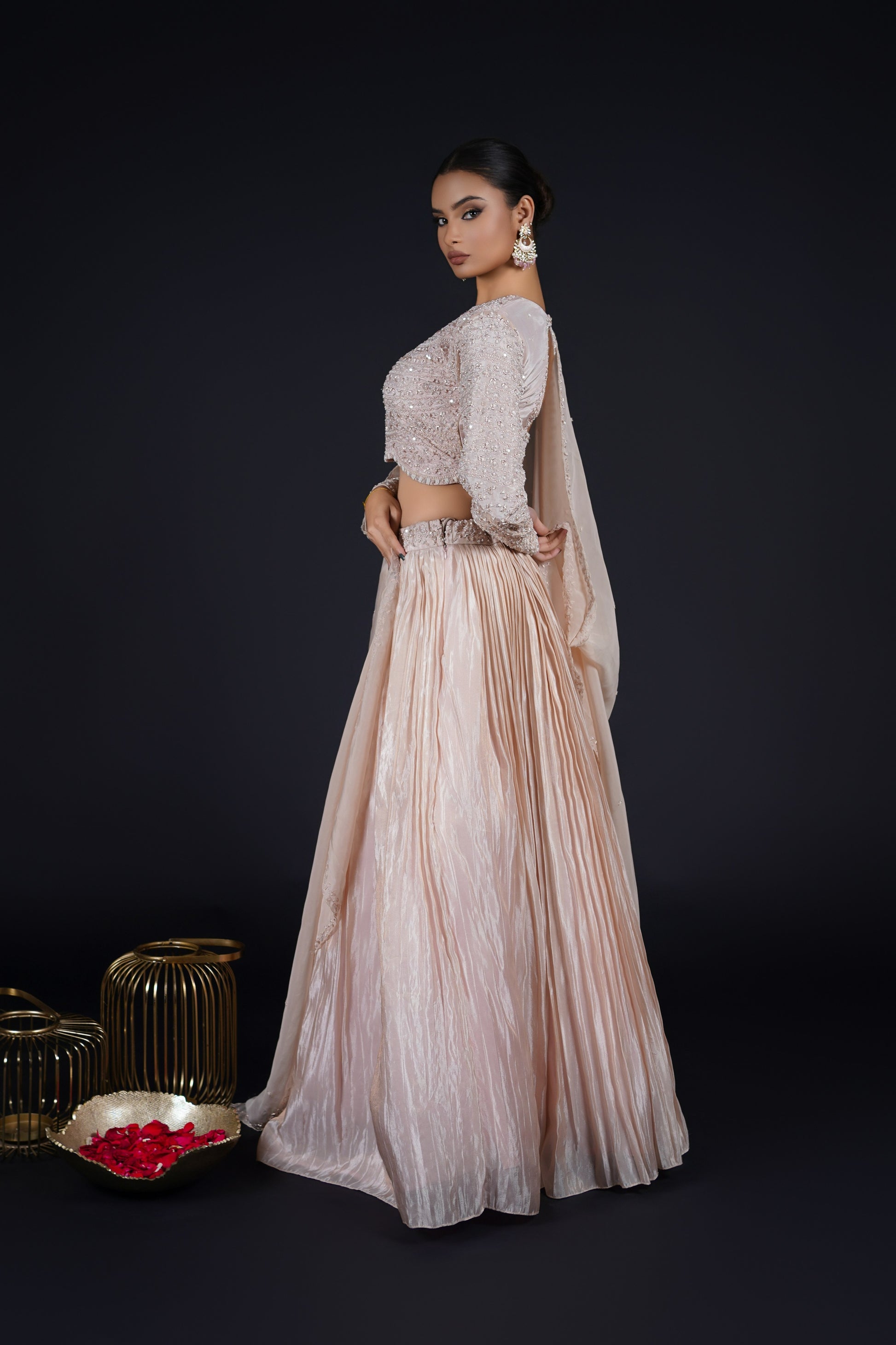 A stunning side-angle pose highlighting the fluid movement of the pleated Tissue Rose Pink Lehenga paired with a delicately embroidered choli.
